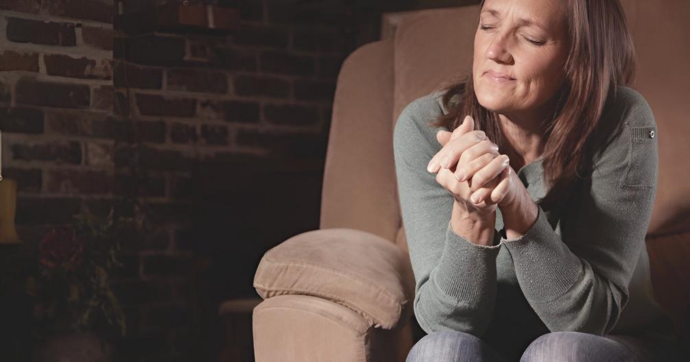 Image of a woman sitting in a chair and praying