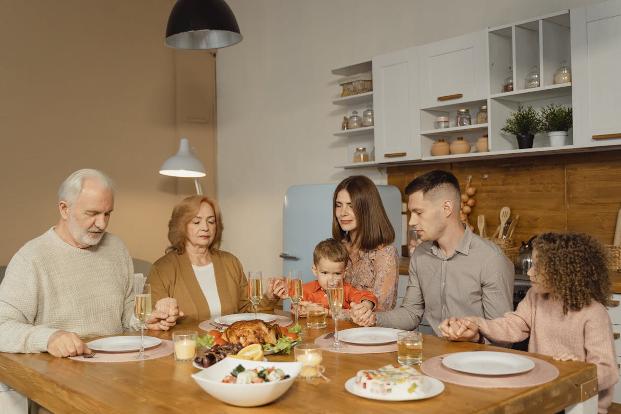 A family gathers for a heartfelt prayer before enjoying a festive meal.