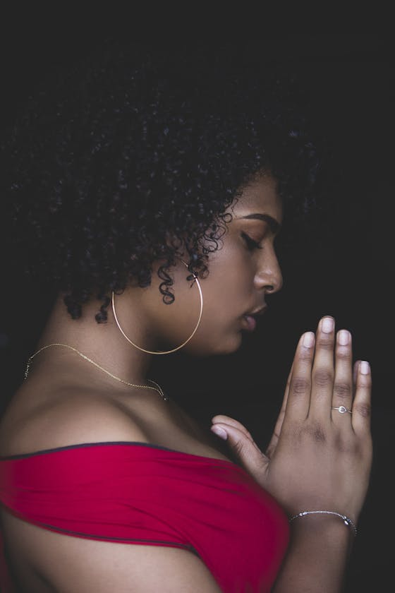 A serene profile of a woman praying in quiet contemplation, captured indoors.