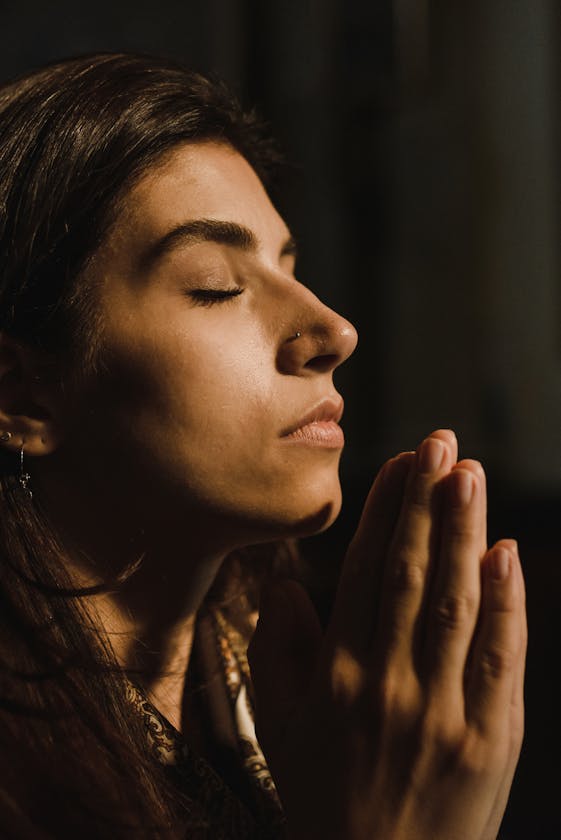 A woman with eyes closed in prayer, conveying peace and introspection.