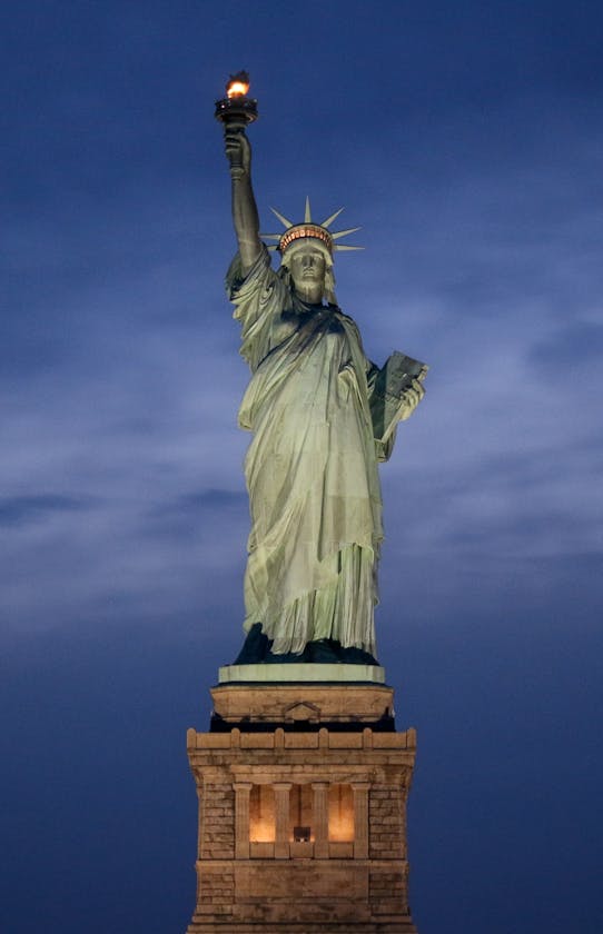 The Statue of Liberty illuminated against a dusky evening sky in New York City.